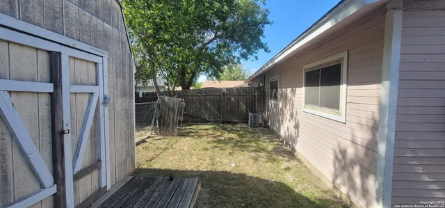 a view of small yard in front of house with wooden fence