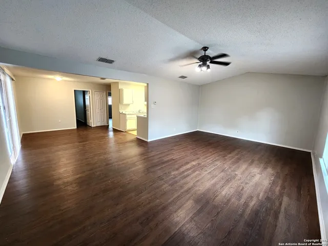 a view of a room with wooden floor and a ceiling fan