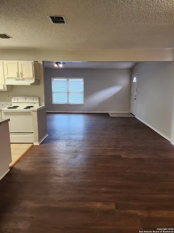 a view of kitchen and empty room with wooden floor