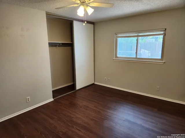 an empty room with wooden floor cabinet and windows