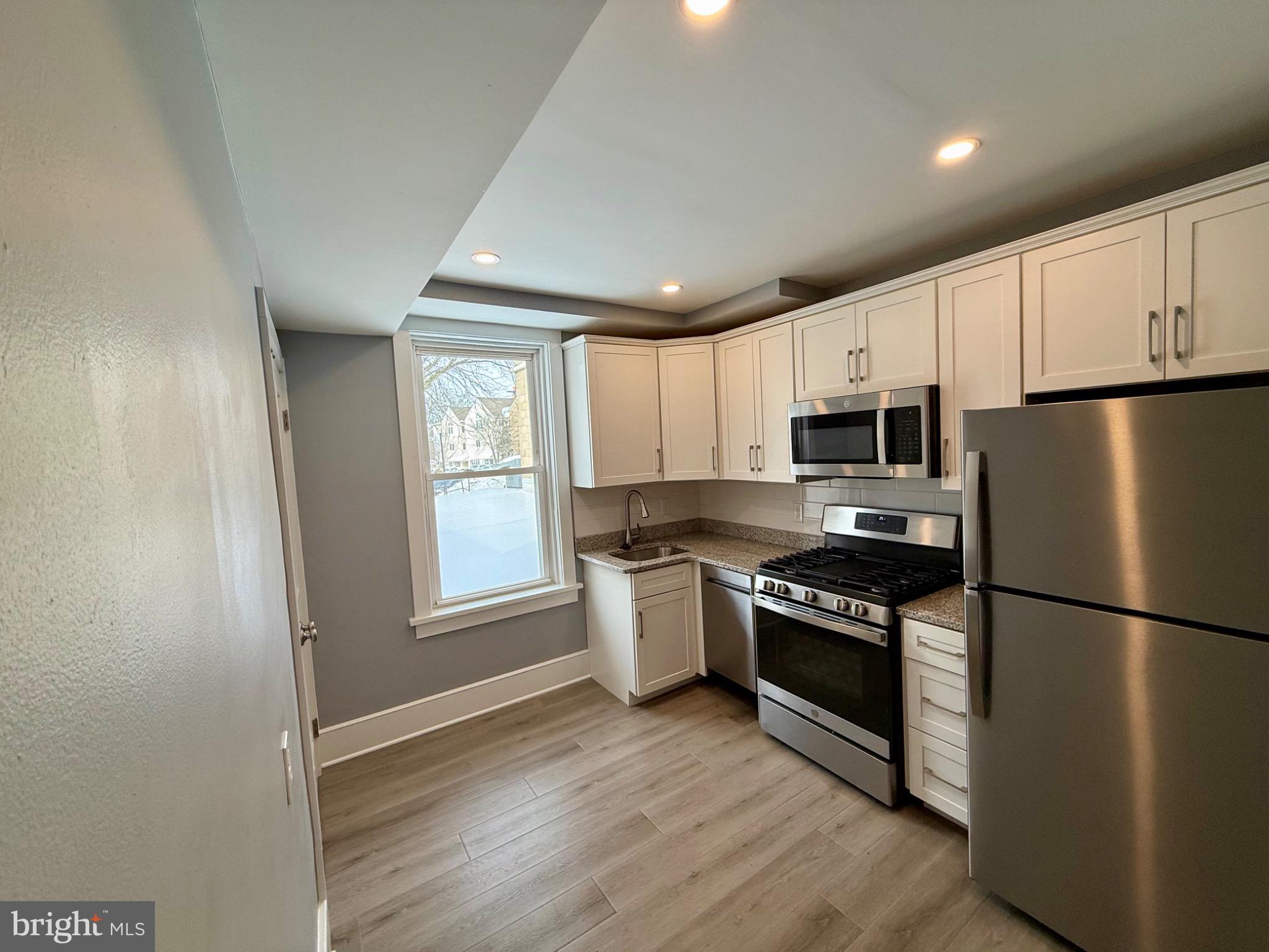 25 West State Street Doylestown, PA 18901 - Photo 2 of 9 a kitchen with granite countertop stainless steel appliances a refrigerator cabinets and wooden floor