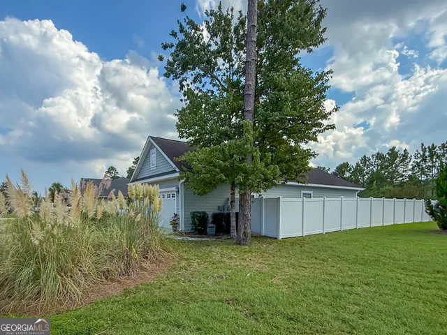 a view of a backyard with large trees and wooden fence