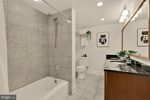 a bathroom with a granite countertop sink a toilet and bathtub