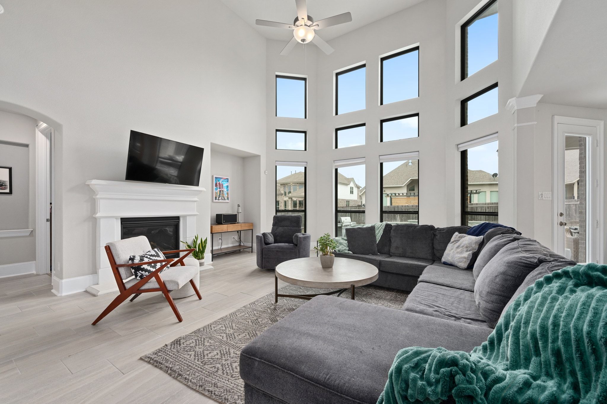 304 Wavy Cattail Cove Georgetown, TX 78626 - Photo 6 of 29 Living room featuring a fireplace, wood tiled floors, a high ceiling, arched walkways, and a ceiling fan