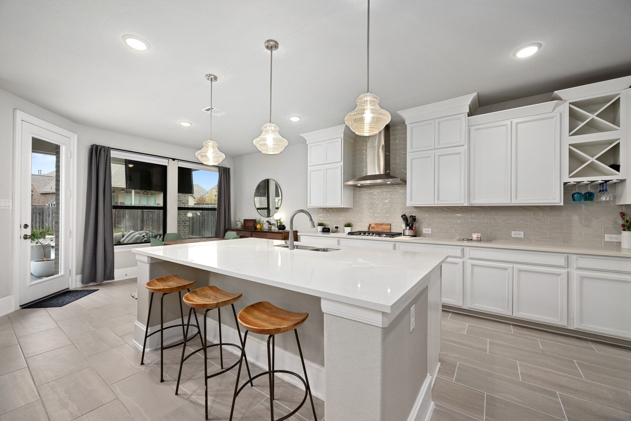 304 Wavy Cattail Cove Georgetown, TX 78626 - Photo 10 of 29 Kitchen featuring white cabinets, a kitchen bar, decorative backsplash, open shelves, and wall chimney range hood