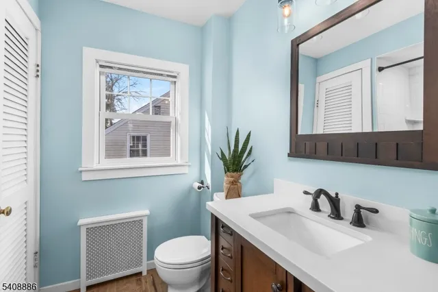 a bathroom with a toilet a sink a mirror a window and vanity