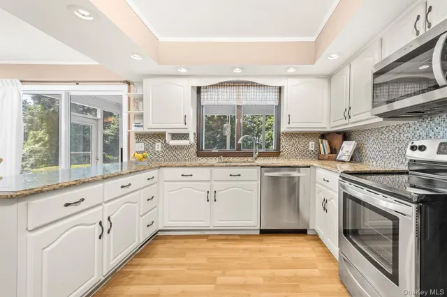 a kitchen with granite countertop white cabinets stainless steel appliances and a sink