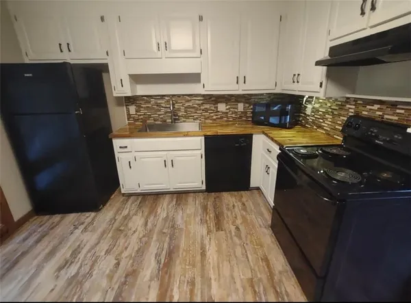 a kitchen with granite countertop a refrigerator stove and white cabinets