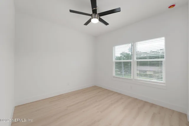 a view of an empty room with a window and wooden floor