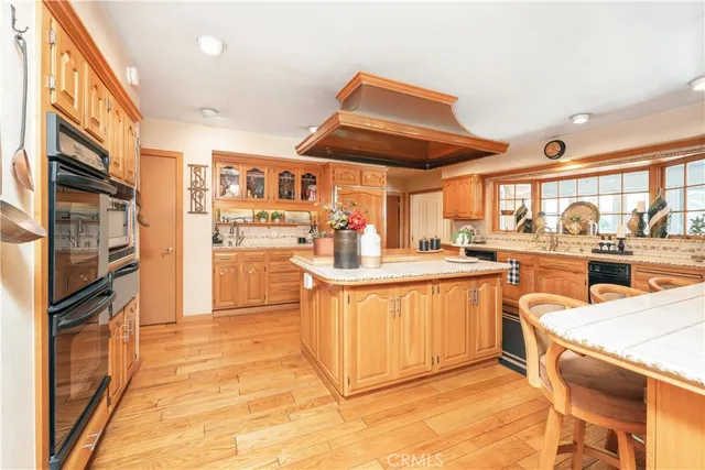 a view of living room kitchen with stainless steel appliances kitchen island granite countertop a sink and cabinets