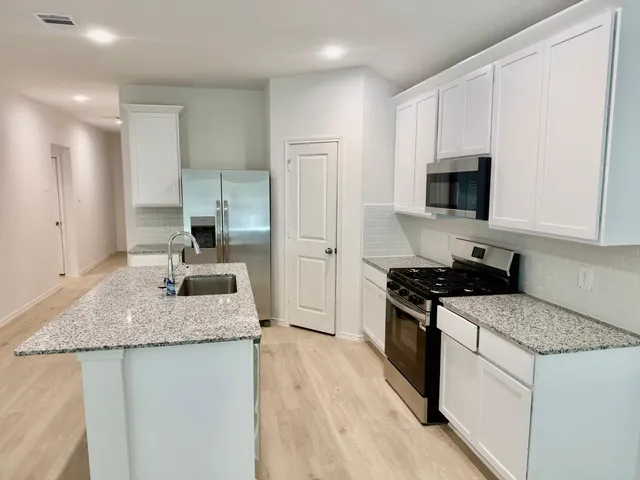 a kitchen with granite countertop a sink stove and refrigerator