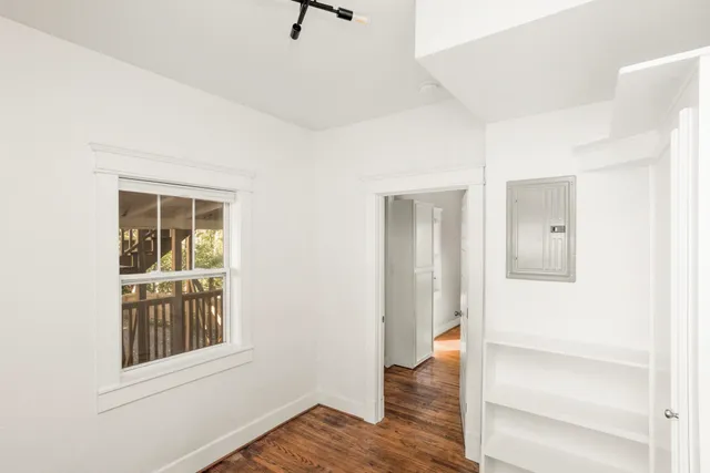a view of an empty room with wooden floor and a window
