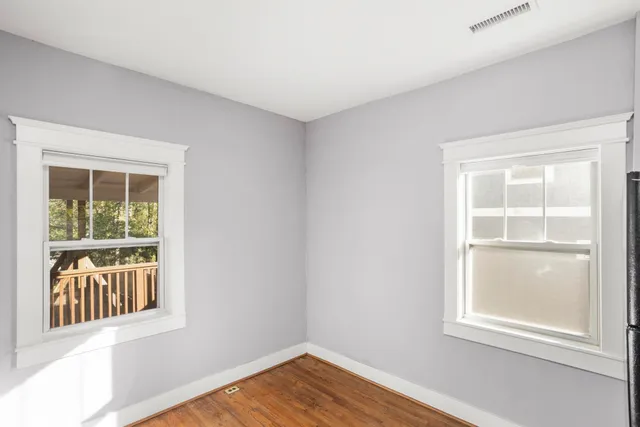 a view of an empty room with wooden floor and windows