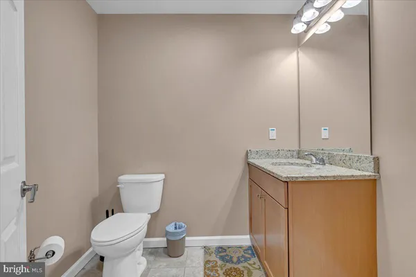 a bathroom with a granite countertop toilet a sink and a mirror