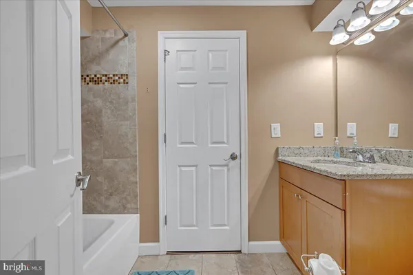 a bathroom with a granite countertop sink a mirror and a bathtub
