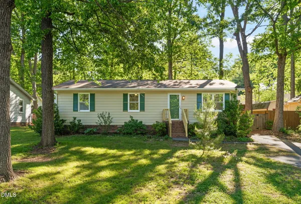 a view of a house with a yard and potted plants and large tree