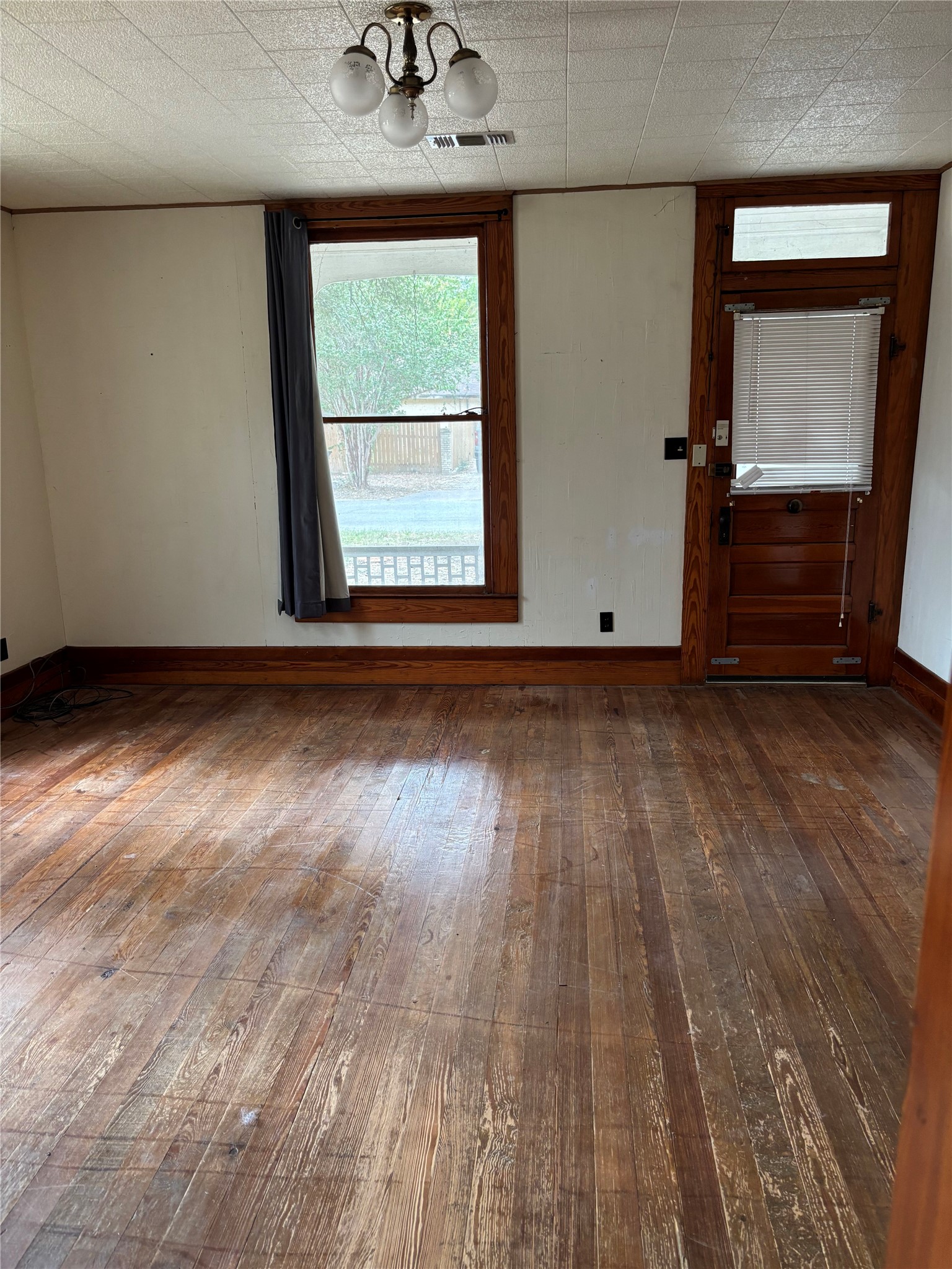 201 South Rio Grande Street Granger, TX 76530 - Photo 6 of 12 Classic hardwood flooring pairs with prominent wood trim framing the windows and door.