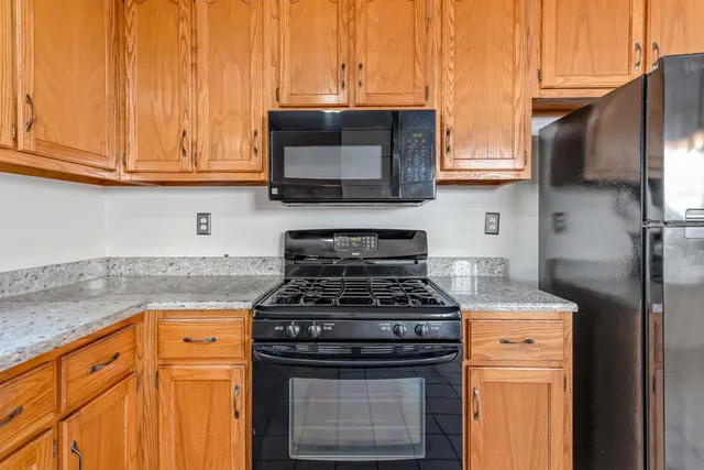 a kitchen with stainless steel appliances granite countertop white cabinets and a stove top oven