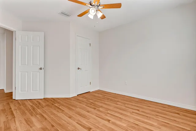 an empty room with a window and a ceiling fan