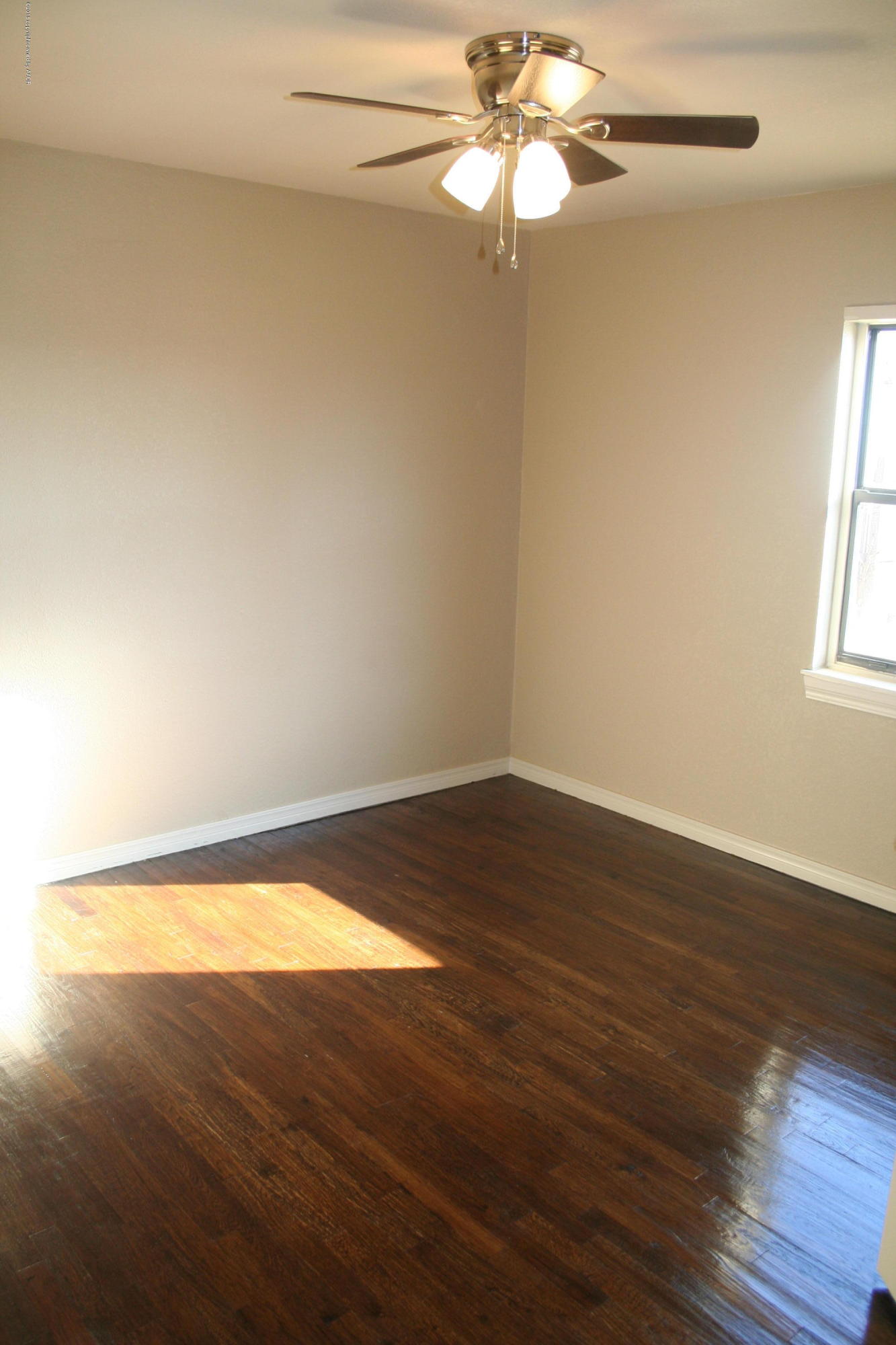 511 Southwest 45th Avenue Amarillo, TX 79110 - Photo 8 of 17 an empty room with wooden floor fan and windows