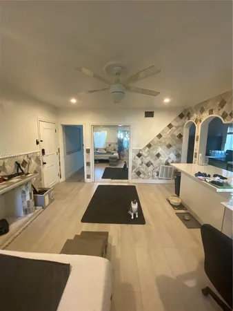 a large kitchen with stainless steel appliances a stove a refrigerator a sink a dining table and chairs with wooden floor