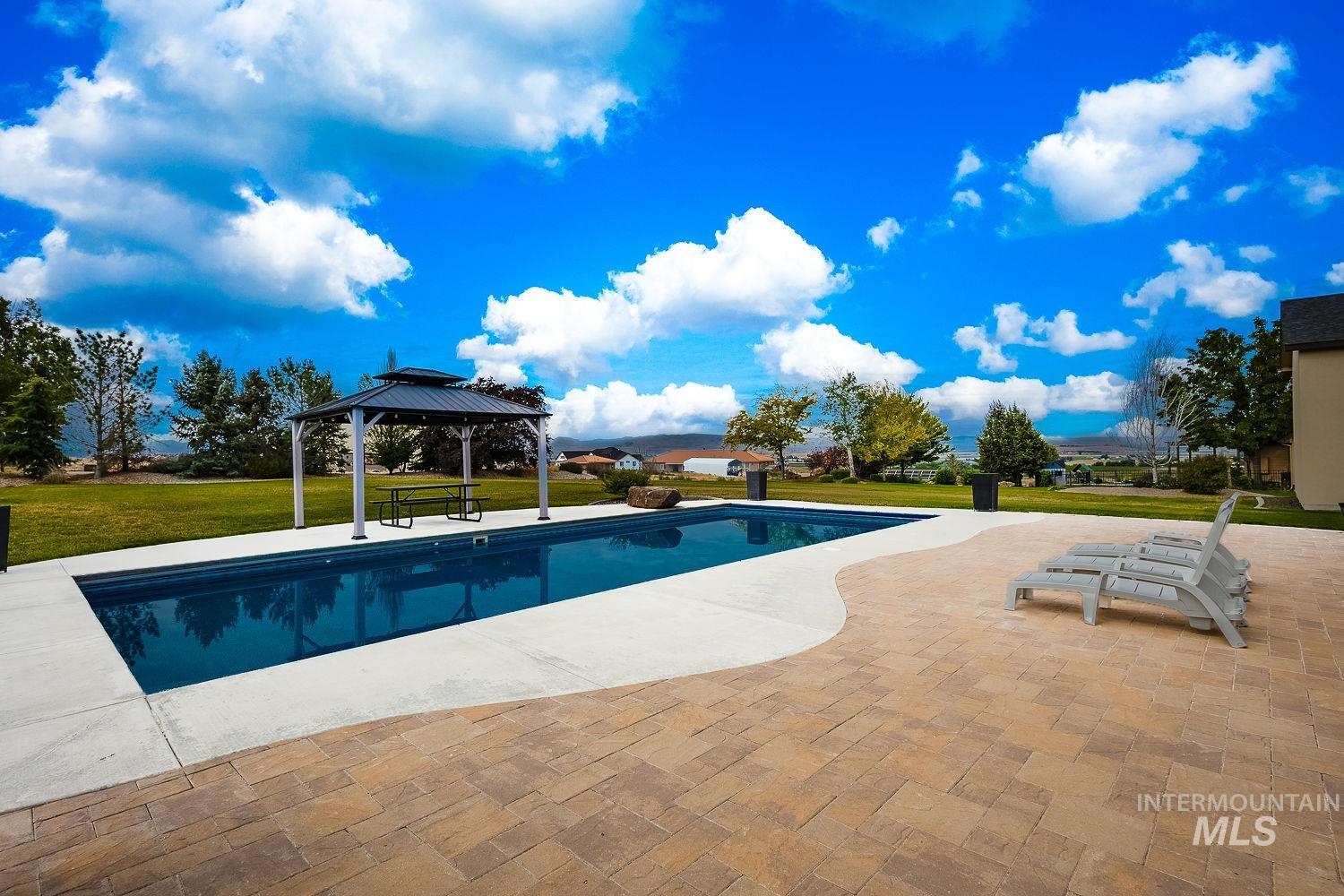 8077 Star Pass Ridge Road Nampa, ID 83686 - Photo 36 of 37 Expansive backyard featuring a rectangular swimming pool, concrete pool decking, and an irregular shaped paver patio