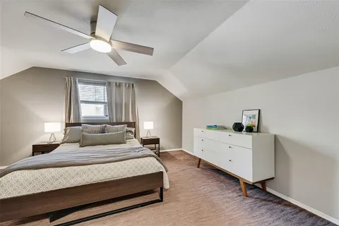a bedroom with a large bed and a chandelier fan