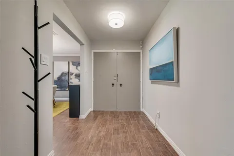 a view of a hallway with wooden floor and a bathroom