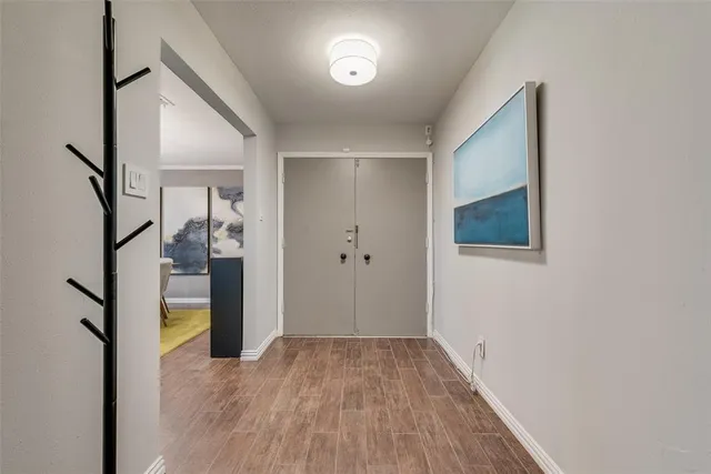 a view of a hallway with wooden floor and a bathroom
