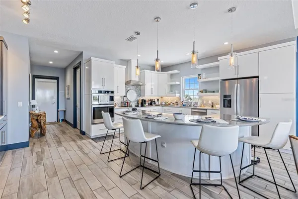 a kitchen with stainless steel appliances a dining table chairs refrigerator and sink