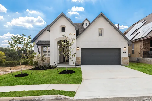 a front view of a house with a garden and trees
