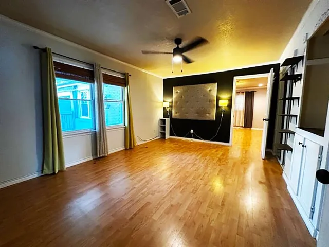 a view of empty room with wooden floor and fan
