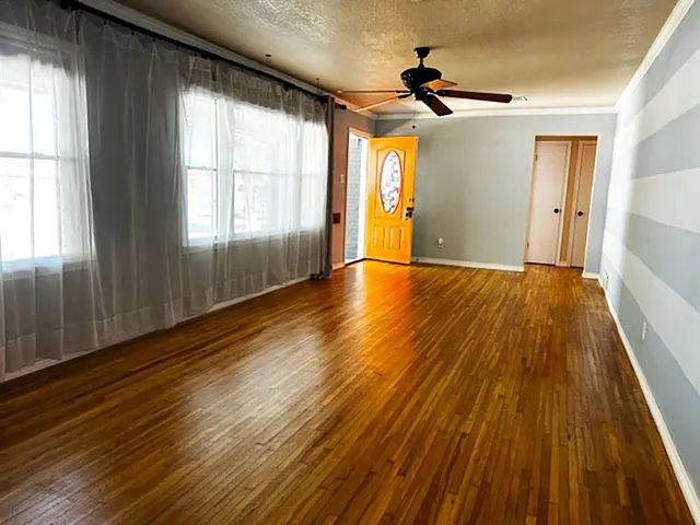 a view of an empty room with wooden floor and a window
