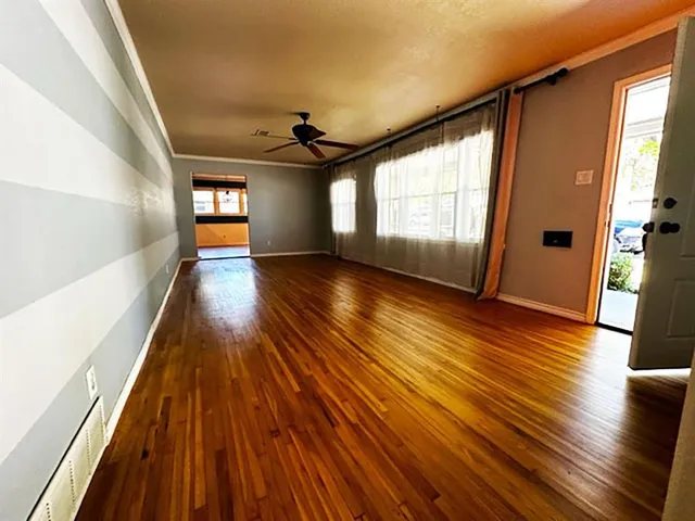 a view of an empty room with wooden floor and a window