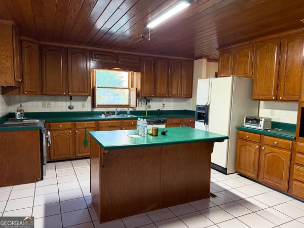 a kitchen with stainless steel appliances granite countertop a refrigerator a sink a stove top oven and a refrigerator