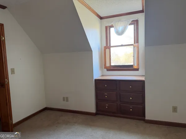 an empty room with a window and a dresser