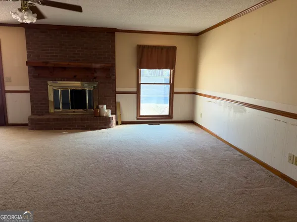a view of an empty room with a fireplace and a window