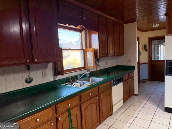a kitchen with granite countertop a sink window and cabinets