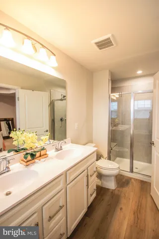 a bathroom with a sink a toilet a mirror and shower