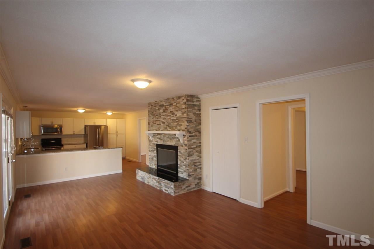 907 Torredge Road Durham, NC 27712 - Photo 5 of 19 a view of a living room a kitchen with a fireplace and wooden floor