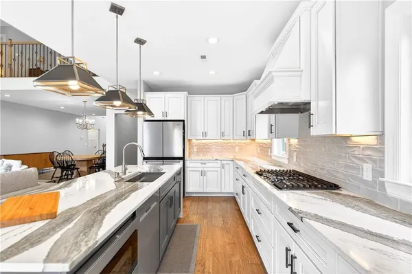 a kitchen with stainless steel appliances granite countertop a sink a stove and a wooden floors