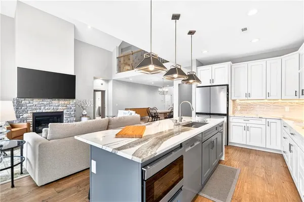 a open kitchen with stainless steel appliances granite countertop a stove and a fireplace with wooden floor