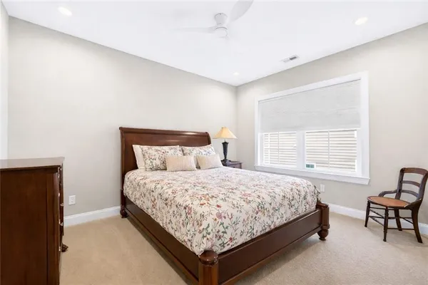 a bedroom with a bed chair and two windows