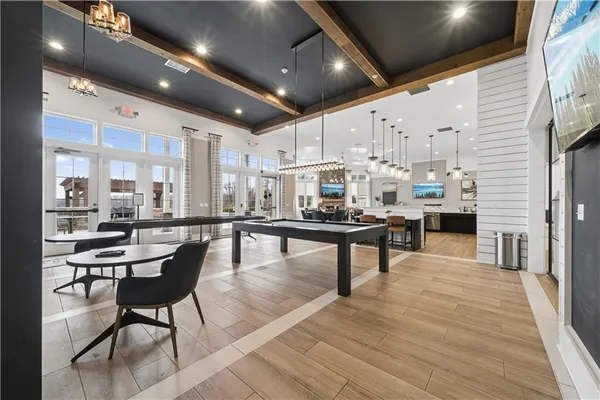 a living room with stainless steel appliances furniture a fireplace and a kitchen view