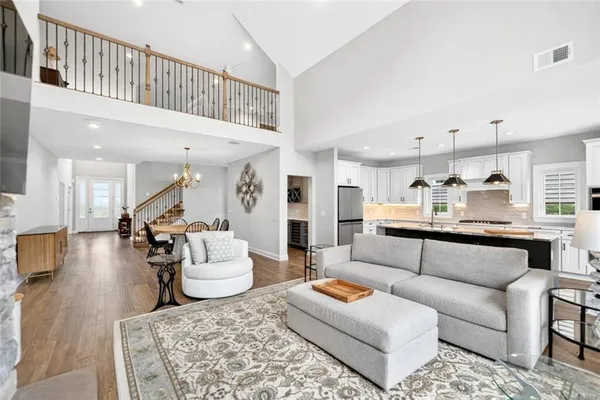 a living room with furniture kitchen view and a wooden floor