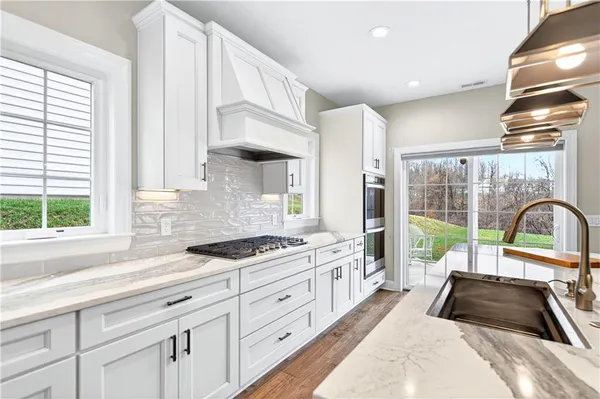 a kitchen with kitchen island a sink appliances cabinets and a large window