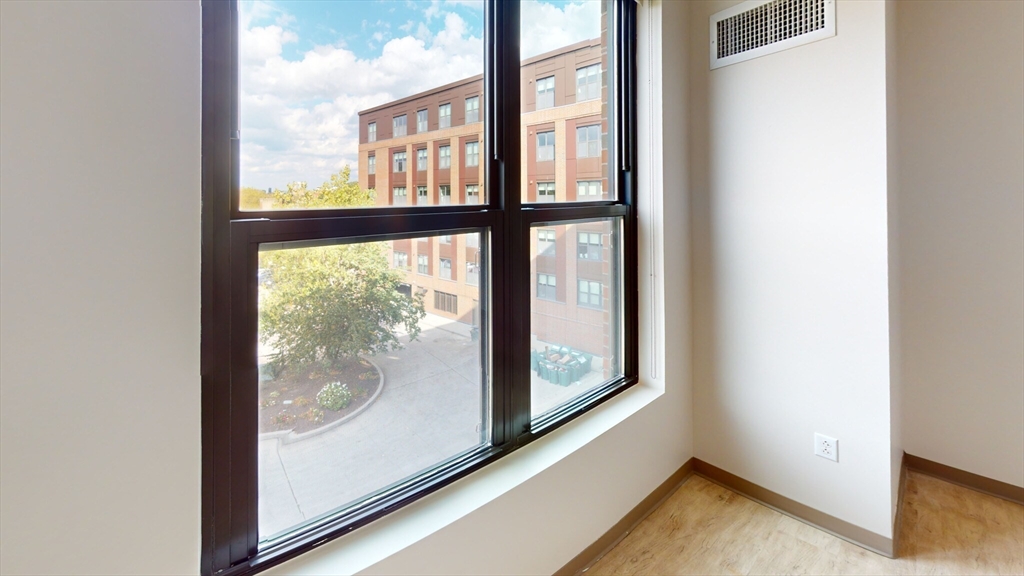 225 Centre Street, Unit 716 Boston, MA 02119 - Photo 4 of 9 an empty room with wooden floor and windows