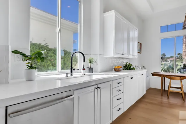 a kitchen with cabinets a potted plant and white appliances