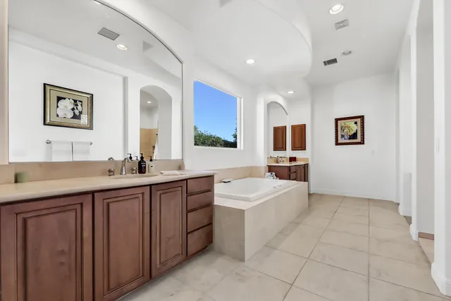 a spacious bathroom with a double vanity sink a mirror and a bathtub