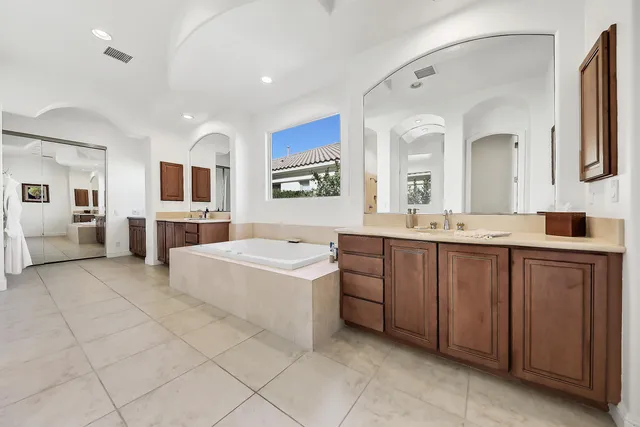 a spacious bathroom with a double vanity sink mirror and bathtub